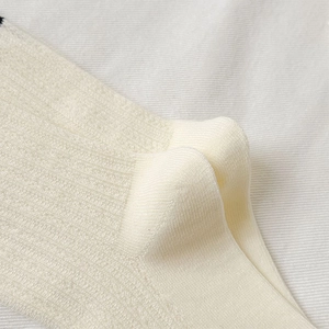 Detailed close-up of ribbed knit texture on cream white cotton blend crew socks
