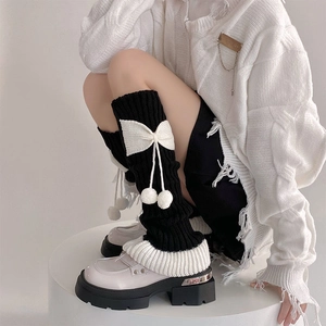 Détail de jambières Lolita noires avec nœuds blancs et pompons en peluche