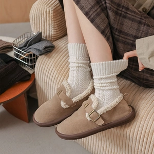 Close-up of white cable knit socks paired with brown suede clogs and lambswool lining