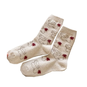 Cute beige knitted socks with cartoon bear patterns and red pom-poms for winter