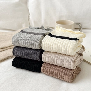 Detailed close-up of six pairs of ribbed cotton socks featuring ruffled lace edges