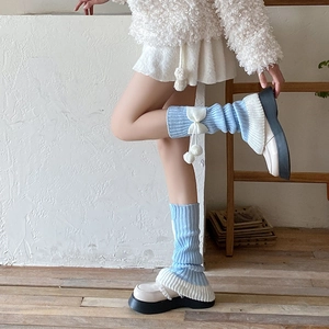Détails des jambières en tricot bicolore bleu et blanc avec nœuds et pompons