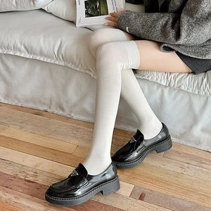 Détail de chaussettes hautes blanches en tricot avec des mocassins à semelles compensées