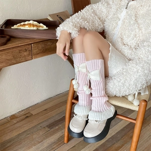Jambières en tricot rose et blanc avec nœuds doux et pompons dans un décor chaleureux