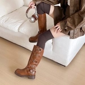 Détail de bottes hautes marron en similicuir avec cinq boucles en métal et semelles épaisses