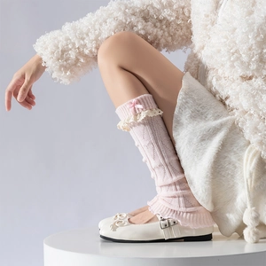 Vue détaillée des jambières en tricot rose avec bordure en dentelle et nœuds