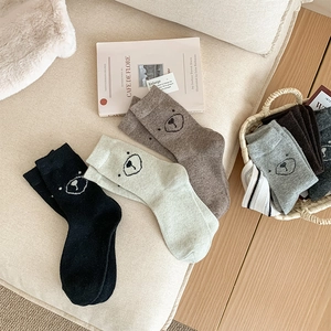 Détail montrant des chaussettes en laine de couleurs variées avec un ours mignon tricoté