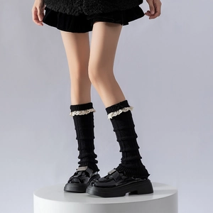 Détail de jambières en tricot noir avec bordure en dentelle blanche et petit nœud