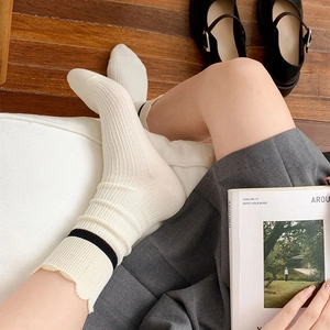 Detail of white knit crew socks with lace trim and black stripes worn with Mary Jane shoes