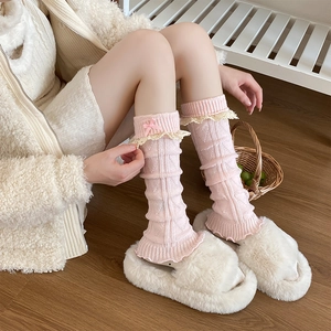 Jambières en tricot rose avec bordure en dentelle et nœud dans un décor chaleureux