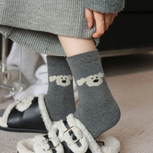 Détail de chaussettes en laine gris foncé avec motif jacquard de petit chien blanc