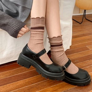 Close-up of khaki ribbed crew socks with lace trim and black platform Mary Jane shoes