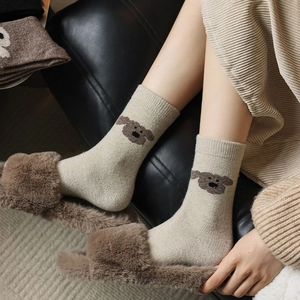 Gros plan de chaussettes en maille beige avec broderie chiot marron et côtes tricot