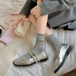 Silberne Mary Jane Ballerinas mit grauen Spitzen-Socken in gemütlicher Wohnatmosphäre