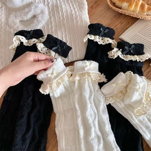 Détail de jambières en tricot avec bordure en dentelle et nœuds sur fond bois
