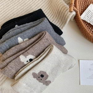 Détails de chaussettes en laine montrant la maille et la broderie ours mignonne