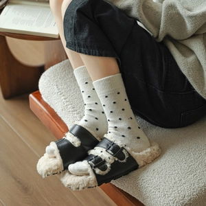Close-up of black leather clogs with plush faux shearling lining and dotted socks