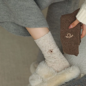 Detail of knit wool socks featuring cute 3D puppy embroidery and textured nep yarn style