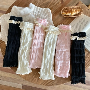Détail de jambières en tricot avec bordure en dentelle et nœuds en noir, blanc et rose