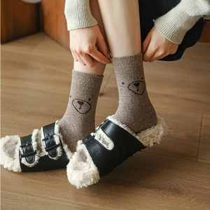 Détail de chaussettes en laine à broderie ours et pantoufles chaudes en peluche noire