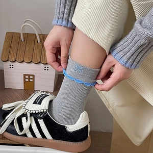 Detailed close-up of lace-edge socks with bow embroidery and retro sneakers