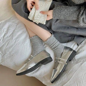 Nahaufnahme silberner Mary Jane Schuhe mit grauen Socken mit Rautenmuster