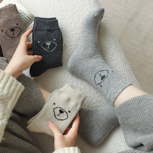 Gros plan de chaussettes en laine épaisses avec broderie ours mignon aux tons neutres