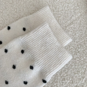 Close-up of thick white wool socks with black polka dots and ribbed cuffs for winter