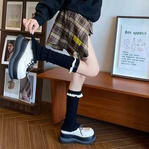 Détail de jambières en tricot avec dentelle blanche et petits nœuds noirs