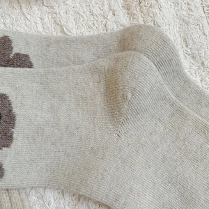 Vue détaillée de chaussettes en laine beige tricotées avec motif floral marron
