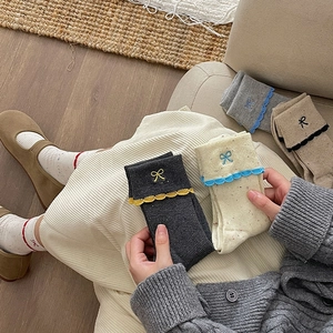 Detail of lace trim cotton crew socks featuring bow embroidery and ribbed knit texture
