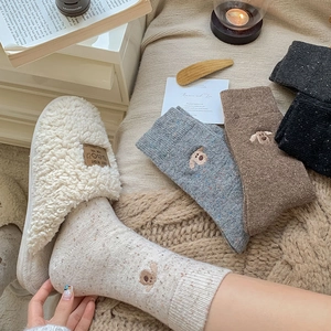 Close-up of wool socks with cute dog embroidery and cozy white fleece slippers