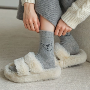 Détail de chaussons en peluche crème et chaussettes à motif ours de style japonais