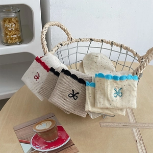 Detail of knit socks with colorful ruffle edges and cute bow embroidery hanging on a basket