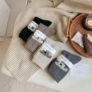 Lot de quatre chaussettes en laine épaisse avec broderie ours dans un décor chaleureux