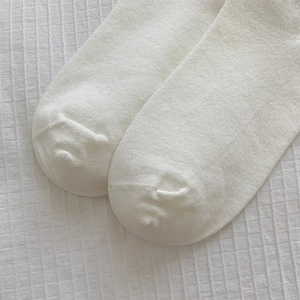 Detailed close-up of white knitted cotton socks toe seams with high-density texture