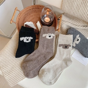 Détail de chaussettes en laine épaisses avec broderie de chien en noir, beige et gris