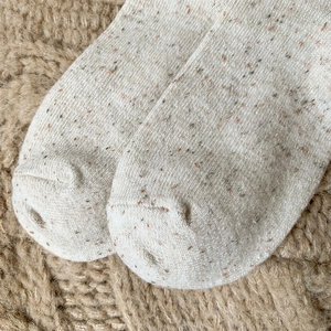Macro shot of speckled wool blend socks toe with colorful dots and fine knit texture