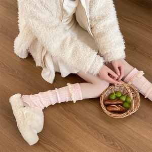 Détails des jambières en maille rose avec dentelle blanche et nœuds décoratifs