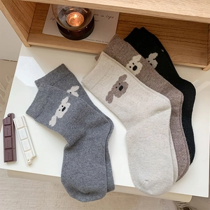 Détail de chaussettes en maille colorées avec broderie chien dans un cadre chaleureux