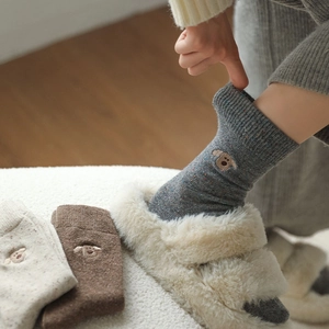 Detail of wool blend socks with puppy embroidery and colorful speckled knit texture