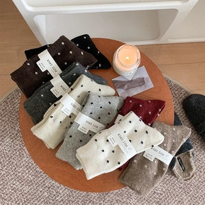 Flat lay of colorful wool polka dot socks neatly arranged on a wooden tray