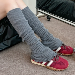 Détail du tricot des jambières grises texturées avec des baskets rouges