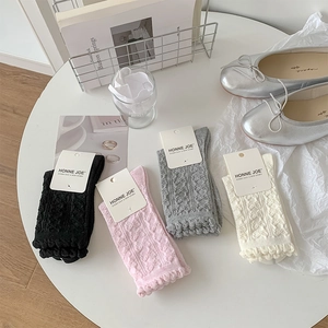 Detail von Rüschensocken in vier Farben mit 3D-Strickherzmustern und Spitzenrändern