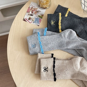 Detail of lace-up socks featuring bow embroidery and colorful speckled knit yarn texture