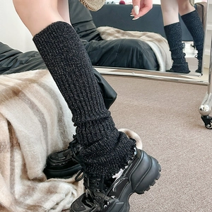 Détail de jambières noires en tricot côtelé avec paillettes argentées et effet plissé