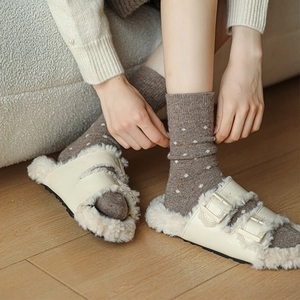 Detail of warm off-white fleece buckles slippers paired with brown polka dot wool socks