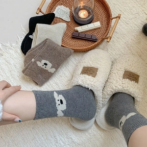 Ensemble d'hiver avec chaussettes en laine et chaussons en peluche sur tapis blanc