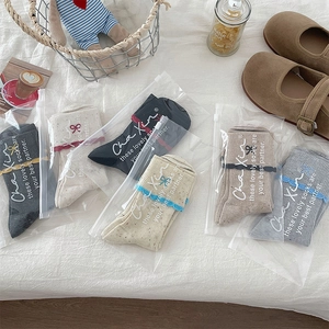 Detail of ruffled socks with bow embroidery in various colors and zipper packaging