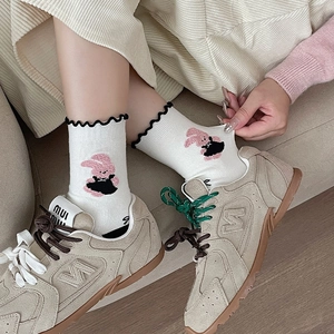 White crew socks with ruffle edge and cute pink rabbit embroidery paired with beige sneakers